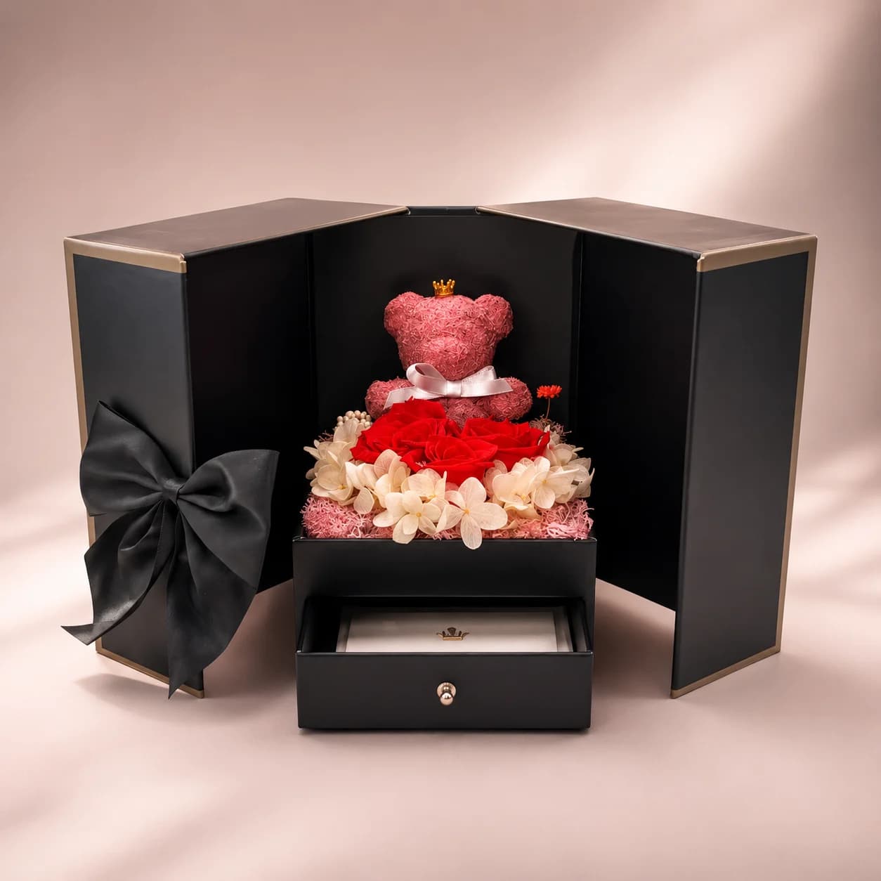 Die Jahrestag-Geschenkbox geöffnet – konservierte Rosen & Teddybär Jahrestag-Geschenkbox geöffnet mit konservierten Rosen und pinkem Teddybär mit Krone