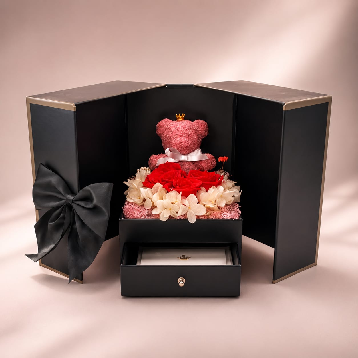 Jahrestag-Geschenkbox geöffnet – konservierte Rosen, pinker Teddybär mit Krone und schwarze Satinschleife